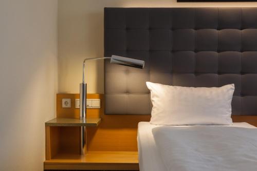 a bedroom with a bed with a headboard and a lamp at ABACUS Tierpark Hotel in Berlin