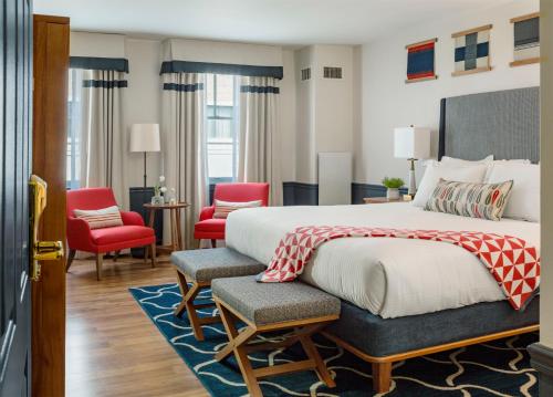 a bedroom with a large bed and red chairs at Portland Harbor Hotel in Portland