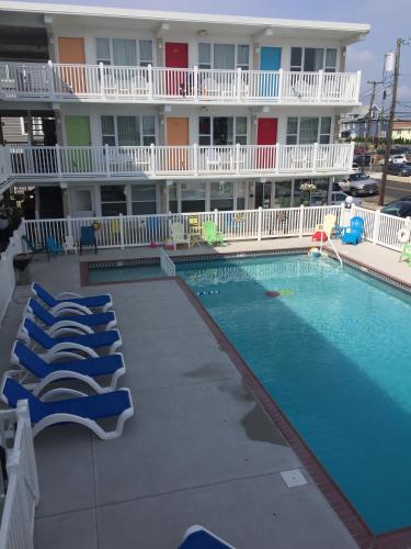 a swimming pool in front of a hotel with lounge chairs at Lollipop Motel in North Wildwood