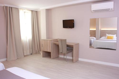 a hotel room with a desk and a mirror at Hotel Villa de Verín in Verín