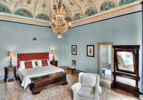 a bedroom with a bed and a chair and a chandelier at Castello Di Monterado in Monterado