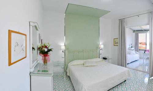 a bedroom with a white bed and a mirror at Hotel Residence Mendolita in Lipari