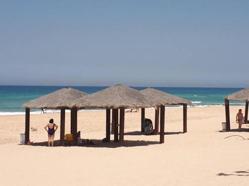 a man standing under umbrellas on a beach at Villa Miami in Ashdod
