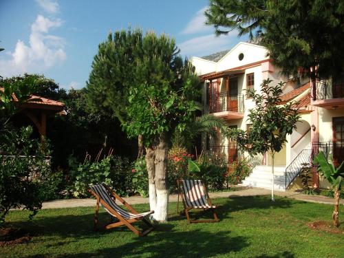 two chairs sitting in the grass in front of a house at İlkiz Beach Hotel in Oludeniz