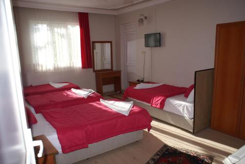 a bedroom with two beds with red sheets at Hotel Dort Mevsim in Pamukkale