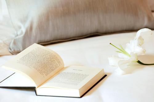 an open book on a bed next to a flower at Boutique Hotel H10 Villa de la Reina in Madrid