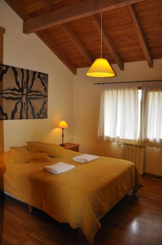 Un dormitorio con una cama grande con una luz amarilla. en Rayen Mapu, en San Carlos de Bariloche
