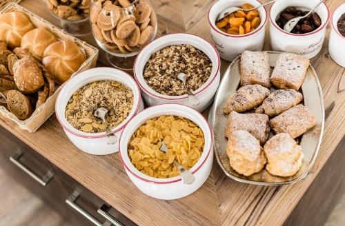 a table topped with bowls of different types of food at Linder Cycling Hotel in Selva di Val Gardena