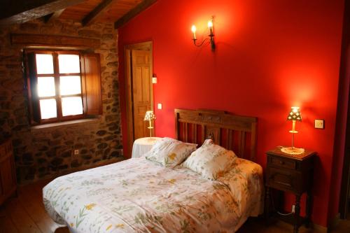 een slaapkamer met een bed met rode muren en een raam bij Casa Rural Ugarte Ojacastro in Ojacastro