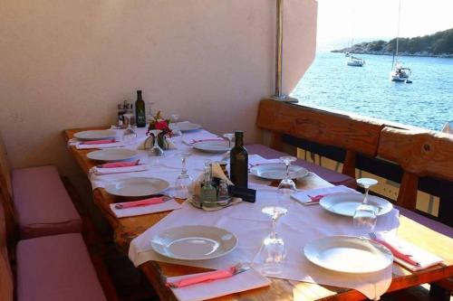a table with plates and wine glasses on a boat at Guesthouse Santor in Lastovo