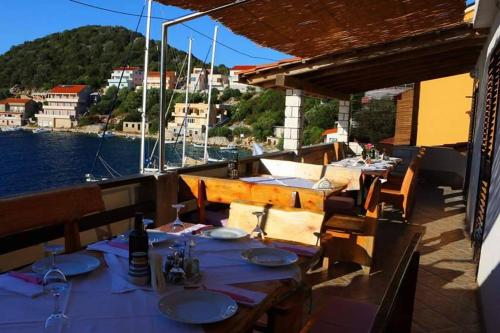a restaurant with tables and chairs with a view of the water at Guesthouse Santor in Lastovo