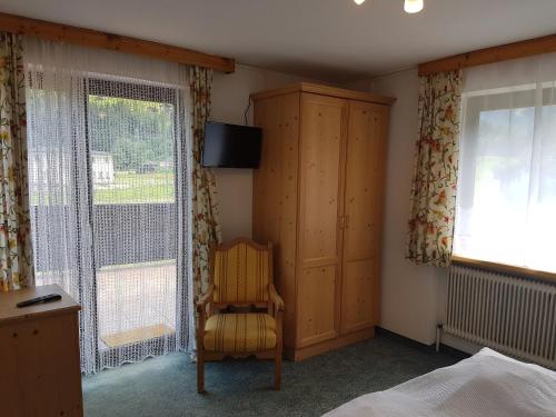 ミッタージルにあるHaus Kropfのベッドルーム1室(ベッド1台、椅子、窓付)
