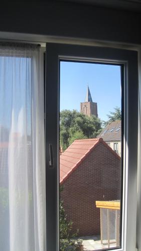 a window with a view of a building and a church at Hotel Restaurant Anno Nu in Oostkapelle