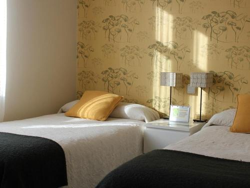 2 camas en una habitación con papel pintado en La Querencia de Valsaín, en La Pradera de Navalhorno
