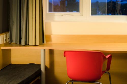 a red chair sitting in front of a desk at Ibis Porto Alegre Assis Brasil in Porto Alegre