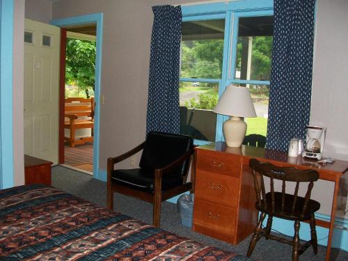 a bedroom with a desk and a chair next to a window at Mohican Motel in Cooperstown