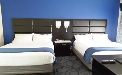 a hotel room with two beds and a blue wall at Holiday Inn Express Hotel & Suites Lawrenceville by IHG in Lawrenceville