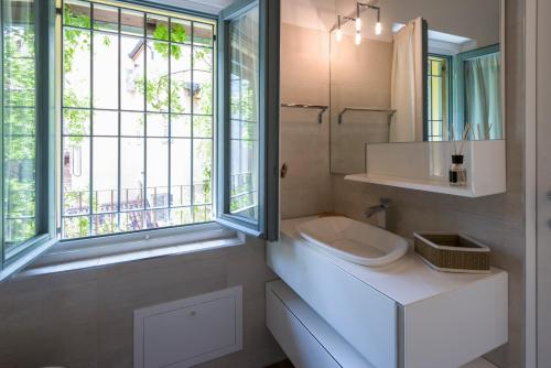Luxury Apartment Milano Centro في ميلانو: حمام أبيض مع حوض ونافذة