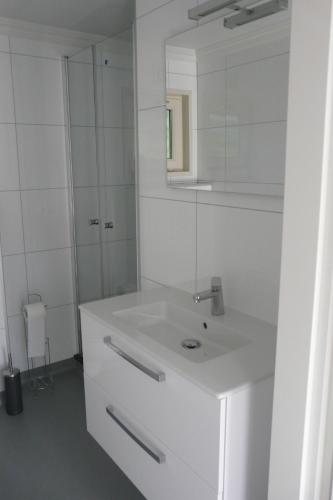 een witte badkamer met een wastafel en een spiegel bij Dolfijn in Ermelo