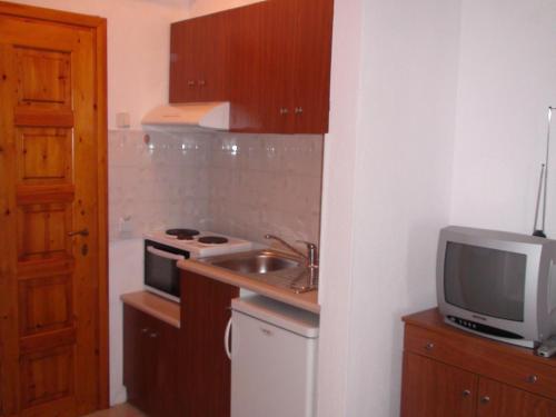 una pequeña cocina con fregadero y TV en Venia Apartments, en Afitos