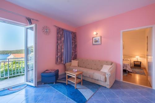 uma sala de estar com paredes cor-de-rosa e um sofá em Apartments Saulan em Molunat