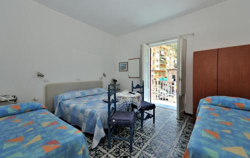 a bedroom with two beds and a table and a window at Hotel Europa in Minori