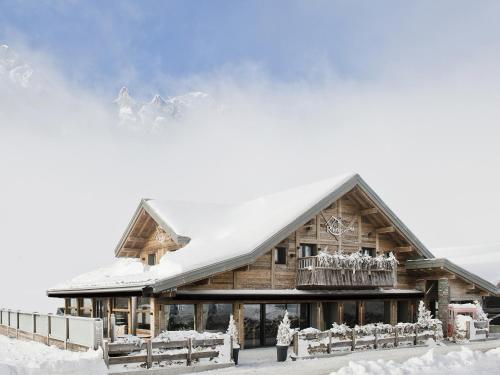 une cabane en rondins avec de la neige sur le toit dans l'établissement Les Rhodos, à La Clusaz