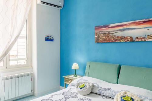 1 dormitorio azul con 1 cama y una pintura en la pared en Casa Lego Napoli, en Nápoles