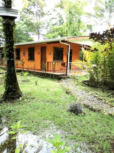 an orange house with a tree in front of it at Cabinas Caribe Luna in Cahuita