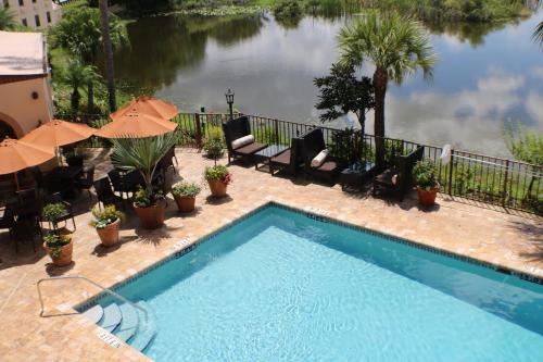 a swimming pool with chairs and umbrellas next to a lake at Inn on the Lakes in Sebring