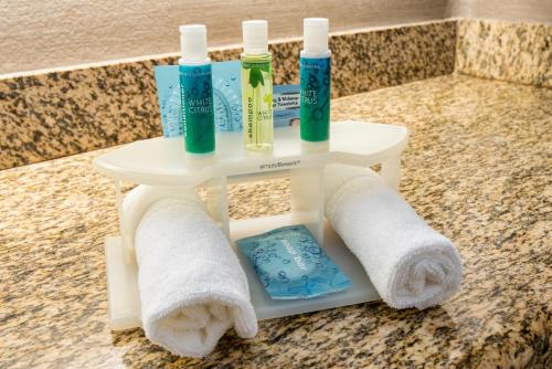 a shelf with three toothbrushes and towels on a counter at Holiday Inn Express & Suites Santa Clara, an IHG Hotel in Santa Clara