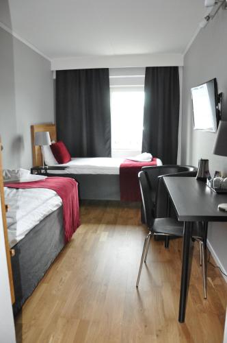 a hotel room with two beds and a table and chairs at City Hotel in Kristinehamn