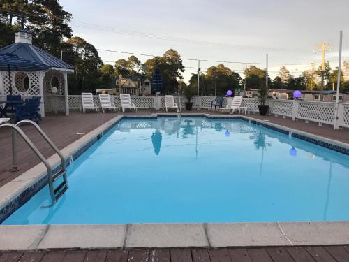 a large blue pool with chairs and a gazebo at Chincoteague Inn in Chincoteague