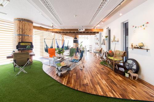a living room with wooden floors and green carpet at 365BASE outdoor hostel in Hamamatsu