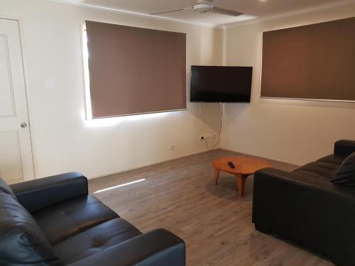 a living room with a couch and a tv and a table at D'Aguilar Hotel Motel in DʼAguilar