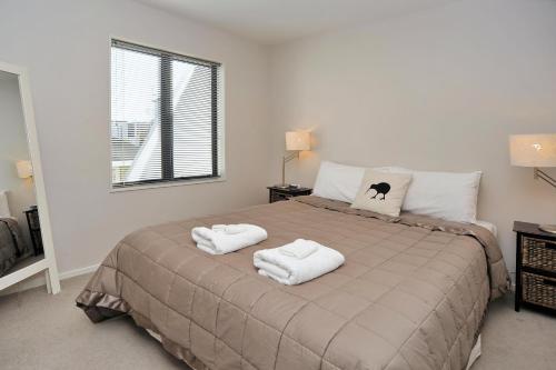 una camera da letto con un letto e due asciugamani di Carlton Villa 3 - Christchurch Holiday Homes a Christchurch