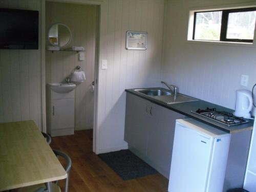 a small kitchen with a sink and a stove at Opunake Beach Holiday Park in Opunake
