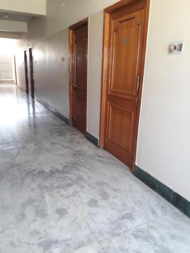 an empty room with wooden doors and concrete floors at Krishna Lodge in Tiruchchirāppalli
