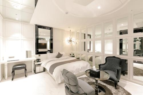 Ischia Hotel في يونغين: غرفة نوم بيضاء مع سرير ومكتب وكراسي