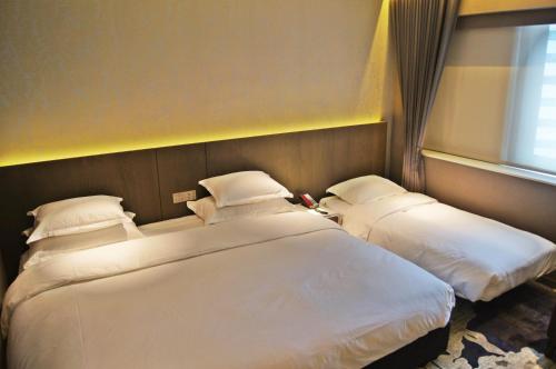 two beds in a hotel room with a window at Brother Hotel in Taipei