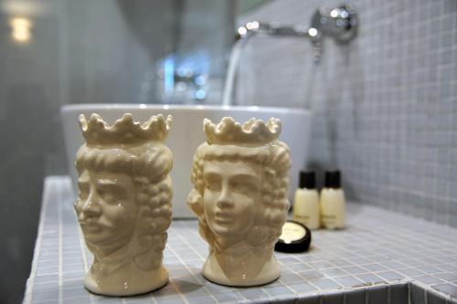 two statues of heads on a counter in a bathroom at Kalote' On The Roof Apartments in Noto