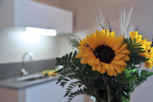 a vase filled with yellow flowers in a bathroom at Kalote' On The Roof Apartments in Noto