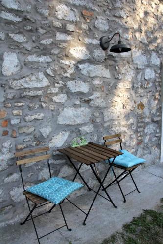 a picnic table and two chairs next to a stone wall at Vánkos in Badacsonyörs