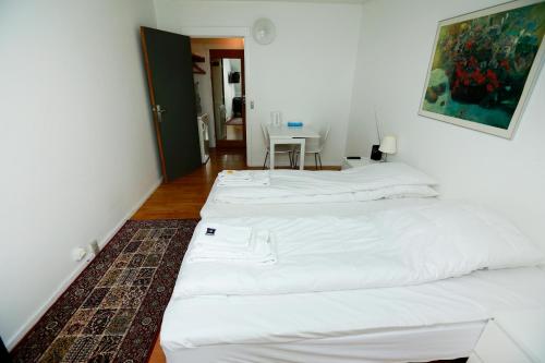 two white beds in a room with a table at Hotel 9 små hjem in Copenhagen