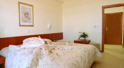 a bedroom with a bed with a white comforter at Hotel Zovko in Slavonski Brod