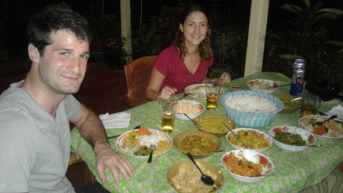 a man and a woman sitting at a table with food at Pinthu Home Stay in Sigiriya