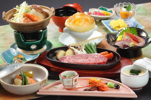 a table topped with plates of food and bowls of food at 湯郷グランドホテル Yunogo Onsen Yunogo Grand Hotel in Mimasaka