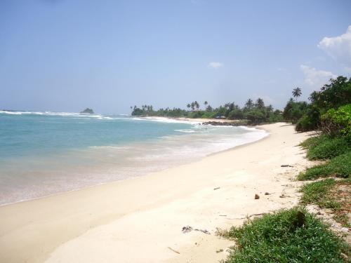 a sandy beach with the ocean in the background at Malika Homestay in Midigama