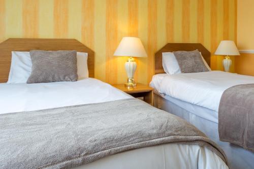 two beds in a hotel room with two lamps at The Grand Burstin Hotel in Folkestone