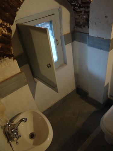 a small bathroom with a sink and a window at Labboo'z Café and Lodge in Maheshwar